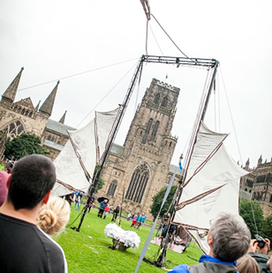 aerialist flies overhead with Durham Cathedral in background