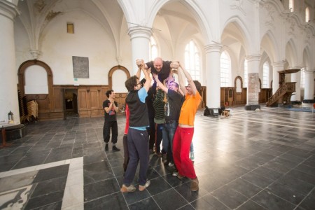 A group of co-workers lifts a college above their heads